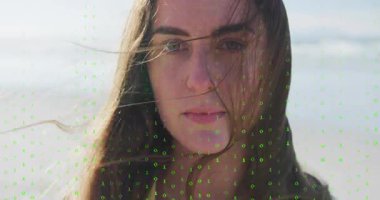 Woman on beach, opening frame initiating green binary code flickering across face for tech demo. Futuristic, digital, cyber, technology, serenity, ethereal, innovation