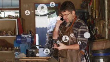 Ahşap işçisi telefon alıyor ve ahşap işçiliği ağını bağlayan canlandırılmış kullanıcı simgelerini izliyor. Sanatçı, dijital bağlantı, yenilikçi, işçilik, atölye, teknik, ağ