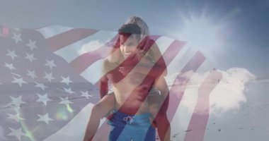 Bayrak dalgalanması, günışığıyla aydınlanan kıyı şeridi boyunca yürüyen ve turizmi canlandıran kadını taşıyan adamı gözler önüne seriyor. Vatanseverlik, eğlence, tatil, açık hava, yaşam tarzı, coşku, arkadaşlık.