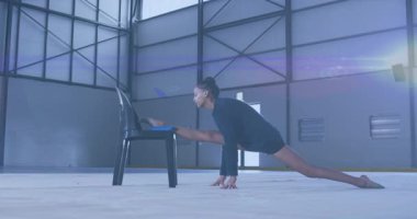 Koltuğa oturan kadın esneklik eğitimi için diz arkasını geriyor. Esneklik, esneme, dansçılık, fitness, endüstriyel, egzersiz, minimalist