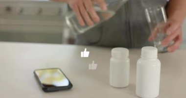 Adam sağlık hizmeti için ilaç şişesini açmadan önce akıllı telefonu yere yerleştirip bardağa su döküyor. Modern, minimalist, sağlıklı, yaşam tarzı, yerli, temiz, işlevsel