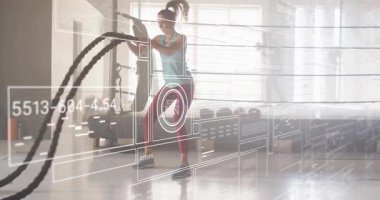 Kadın savaş halatlarını sıkıca kavrıyor, fitness verileriyle ritmik vuruşlar yapıyor. Dinamik, güç, egzersiz, modern, enerjik, teknoloji, atletizm