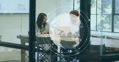 İş toplantısında dizüstü bilgisayara bakan iki profesyonel, dünya rotasyonuna başlıyor, grafikler yükseliyor. İşbirliği, yenilik, teknoloji, veri analizi, takım çalışması, modern ofis, dijital dönüşüm