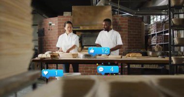 Hamur düzenleme, fırıncı meslektaşlar somun şekillendirirken tepkime simgeleri yükselirken sosyal vızıltıyı gösteriyor. Esnaf, aşçı, ısınma, takım çalışması, işçilik, iç mekan, nostalji.