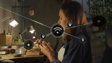 Elektronik panodaki lehimleme kablolarında kadın teknisyen parçaları güvene almak ve ağ simgelerini canlandırmak için. Elektronik, ağ oluşturma, yenilik, işçilik, teknoloji, yaratıcılık, çalışma alanı
