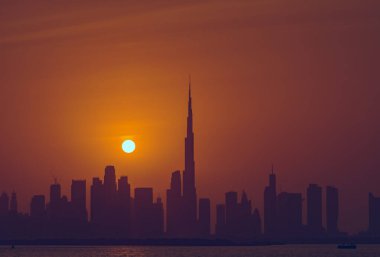 Dubai 'nin güzel gün batımı manzarası Burj Halife silueti ile birlikte. Panoramik şehir manzarası seyahat, başyazı veya ticari kullanım için mükemmel. Burç Halife canlı turuncu bir gökyüzüne karşı siluetlendi.