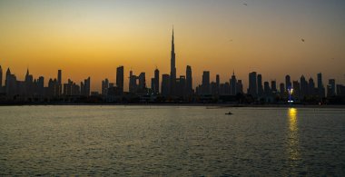 Burj Halife siluetiyle Dubai ufuk çizgisinin güzel gündoğumu manzarası. Panoramik şehir manzarası seyahat, başyazı veya ticari kullanım için mükemmel. Burç Halife canlı turuncu bir gökyüzüne karşı siluetlendi.