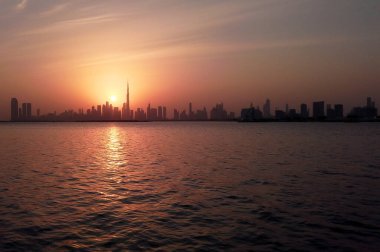 Dubai 'nin güzel gün batımı manzarası. Burj Halife silueti, Dubai Creek Limanı' ndan yakalandı..