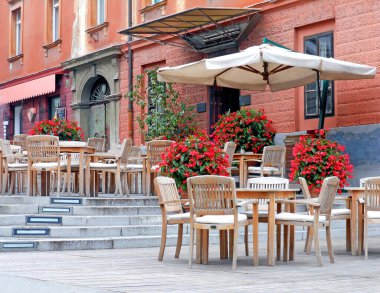 Ljubljana Slovenya 26 Temmuz 2012. Boş kafe terası, ahşap mobilyalar ve renkli bina perileri boyunca canlı çiçekler.