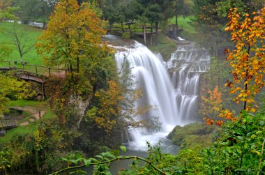 Rastoke Hırvatistan. 8 Ekim 2015. Yağmurlu bir öğleden sonra yeşil ve portakal ağaçlarının ortasında görkemli bir şelale görüldü.