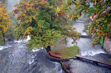 Rastoke Hırvatistan. 8 Ekim 2015. Yağmurlu bir öğleden sonra yeşil ve portakal ağaçlarının ortasında görkemli bir şelale görüldü.