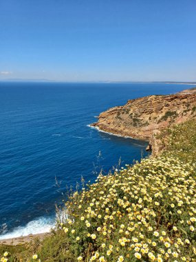 Sesimbra Portekiz 'deki Cape Espichel sahil şeridinin panoramik manzarasında engebeli uçurumlar turkuaz okyanus ve güneşli bir günde sakin bir çakıl taşı plajı var.