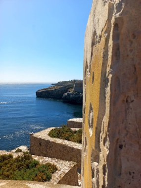 Penis, Portekiz. 21 Temmuz 2024 Engebeli kireçtaşı kale duvarları Peniche 'deki açık mavi Atlantik Okyanusu' na bakan parlak öğle güneşi altında