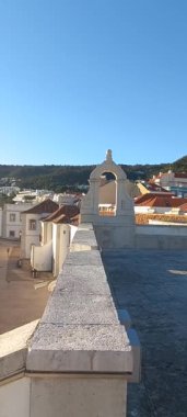 Çatlak kıyı şeridi ılık güneş ışığıyla yıkanmış köpüklü dalga hattını ve Susimbra 'nın ötesindeki derin mavi Atlantik ufkunu çerçevelemiş..