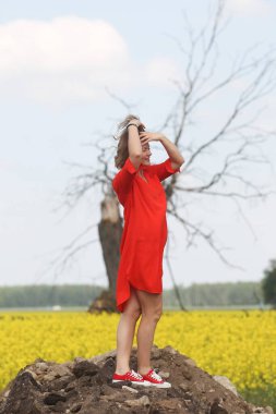 Kırmızı elbiseli güzel bir kadın tarlada poz veriyor.