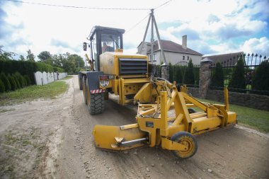 Yol ayrımcısı buldozer, yoldaki yerleşim yerlerini dengeliyor.