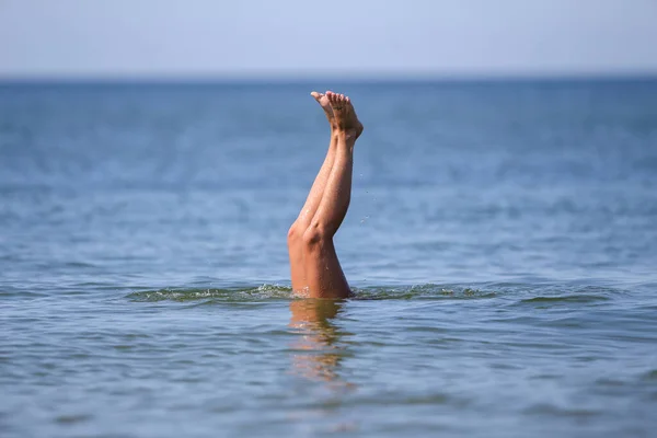 Drowning woman\'s legs sticking out of sea