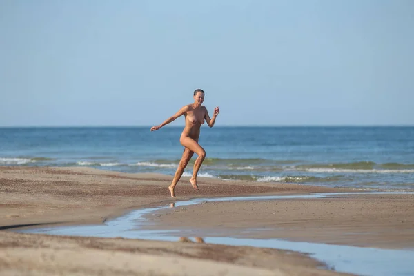 stock image Beautiful young woman jumping on the beach