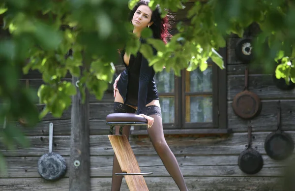 스타킹을 다리를 아름다운 머리의 여자가 나무집 근처에서 포즈를 취하고 있습니다 — 스톡 사진
