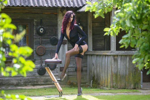 스타킹을 다리를 아름다운 머리의 여자가 나무집 근처에서 포즈를 취하고 있습니다 — 스톡 사진