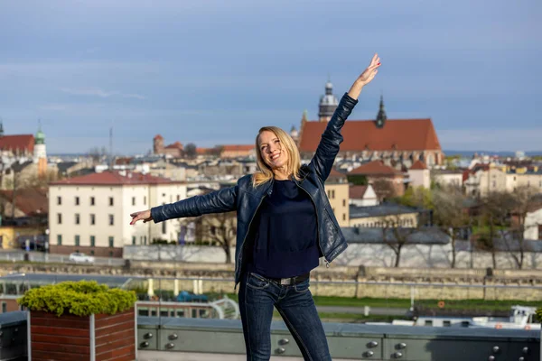 stock image Beautiful woman in a blue jacket, dark shirt and blue jeans posing against the background of the city of Krakow