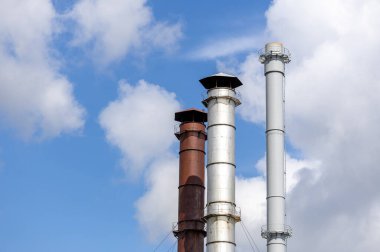 Bulutlu mavi gökyüzüne karşı endüstriyel bir fabrikanın dumanı.