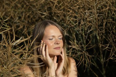 Yüzünde çiller olan güzel bir genç kadının portresi. Arka planda sonbahar olgunlaşmış kanola.