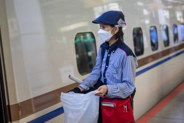 Japonya 'da bir tren istasyonunda çöp toplayan bir kadın, tren vagonunun yanında.