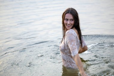 Beyaz şeffaf elbiseli çekici kız akşamları suda banyo yapıyor.