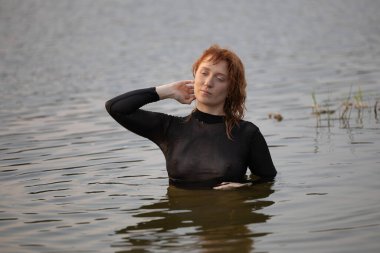 Suyun içinde siyah taytlı güzel kızıl saçlı genç bir kadının portresi.