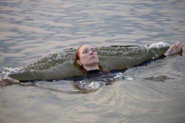 Suyun içinde siyah taytlı güzel kızıl saçlı genç bir kadının portresi.