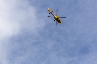 Mavi gökyüzünde uçan sarı helikopter