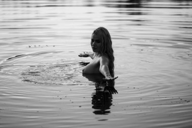 Suda poz veren genç ve güzel bir kadın. Açık havada seksi sarışın.