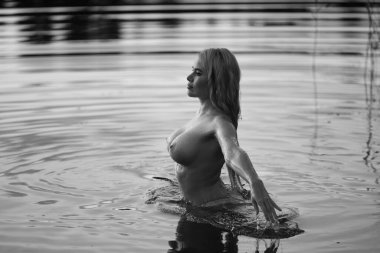 Suda poz veren genç ve güzel bir kadın. Açık havada seksi sarışın.