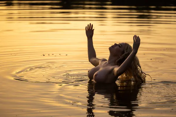 Suda poz veren genç ve güzel bir kadın. Açık havada seksi sarışın.