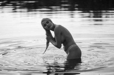 Suda poz veren genç ve güzel bir kadın. Açık havada seksi sarışın.