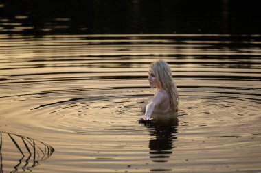 Suda poz veren genç ve güzel bir kadın. Açık havada seksi sarışın.
