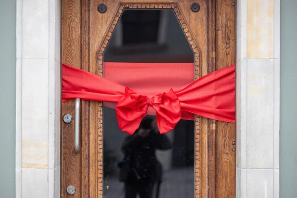 Decorative Red Ribbon Bow Adorning a Wooden Door for a Festive Celebration
