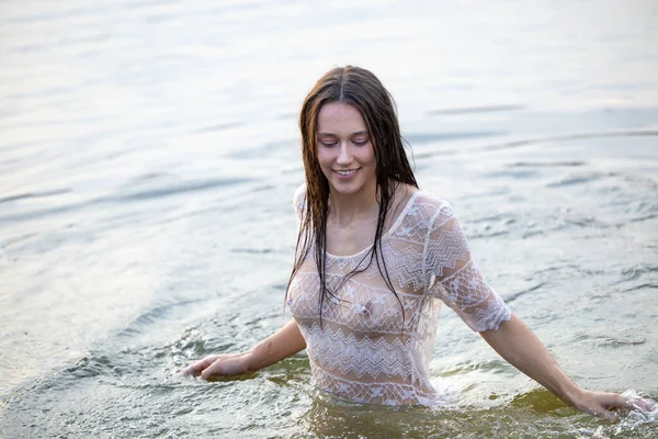 Beyaz şeffaf elbiseli çekici kız akşamları suda banyo yapıyor.