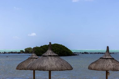 Sun umbrella and beach beds on tropical coastline, in Mauritius clipart
