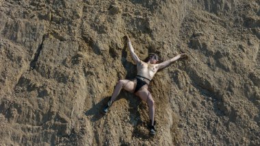 Çakıl çukurunda poz veren yuvarlak gözlükleri ve delikli bacakları olan güzel seksi kadın.