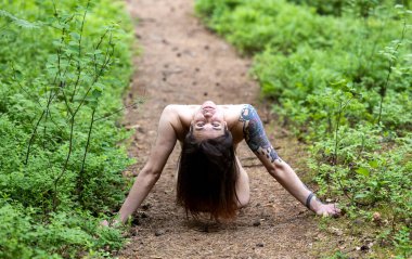 Güzel, koyu renk saçlı bir kız. Orman yolunda yatarken poz vermek
