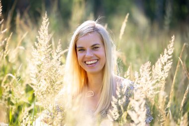 Mutlu tatlı kız güneşli bir yaz günü çiçekli çayırda eğleniyor.