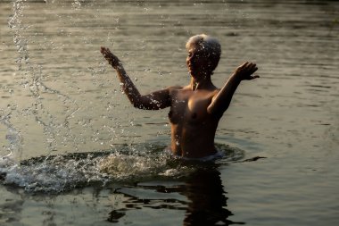 Gün batımında mutlu bir kadın, göle sıçrıyor, ılık bir sonbahar akşamı.