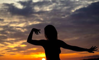 Bir kadının silueti akşam gökyüzüne karşı çarpıcı sonbahar renklerinde gökyüzü