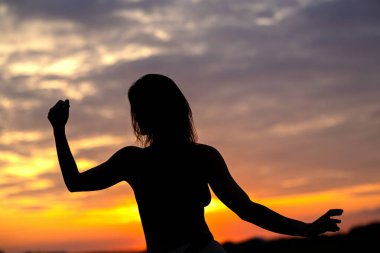 A woman's silhouette against the evening sky, with a stunning autumn-colored sky clipart