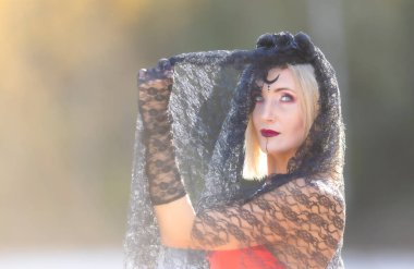 Blonde with Halloween makeup, black veil, red dress, and lace gloves: the elegance of darkness. Portrait of a beautiful woman clipart