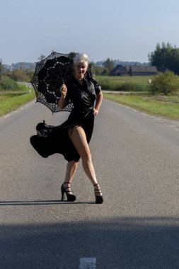 Black Elegance on the Road: A Woman with a Lace Parasol Strolling Along a Countryside Path clipart