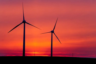 Renewable energy: a wind turbine against a red sky clipart