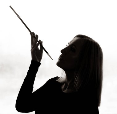 Işığa dayanmış güzel bir kadının portresi, elinde bir sigara tutacağı.